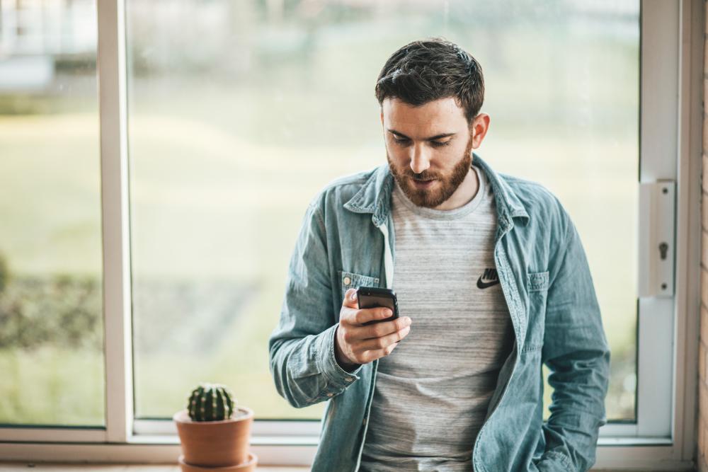 Male looking at mobile phone in front of large window