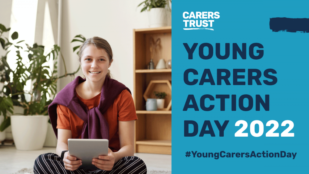 Young female sat crossed legged smiling at camera holding tablet device. Blue banner to right of image with Carers Trust logo, text 'Young Carers Action Day 2022 #youngcarersactionday'