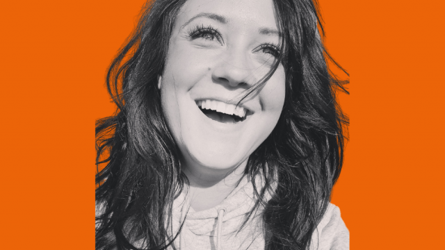 Black and white photo of Abby Lewis smiling on orange background