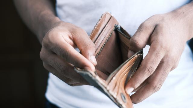 Person holding empty brown wallet open, wearing white t-shirt