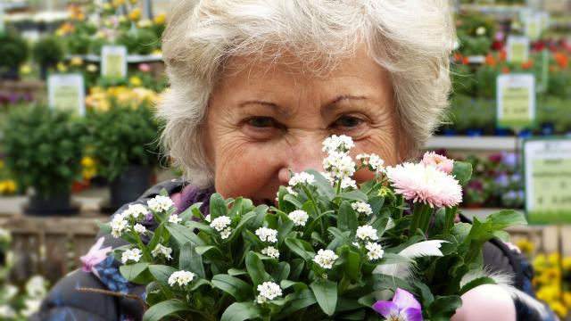 Older lady smiling behind bouquet of flowers
