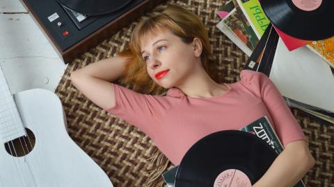 Lady lying down with records around her and white guitar