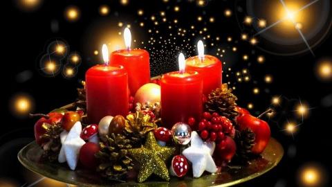 Christmas candle centrepiece, four red candles lit in a dark room with fairly twinkle light background