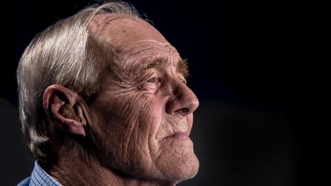 Older male looking towards the right. Dark background.