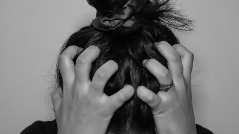 Black and white image of female with head in hands in distress