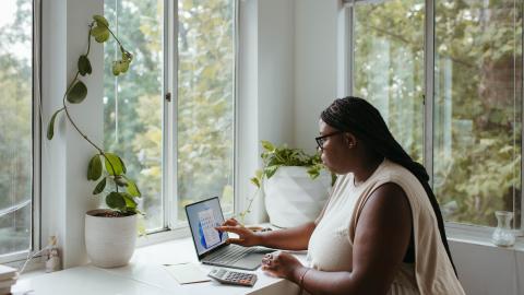 Lady touching computer screen sat at white desk