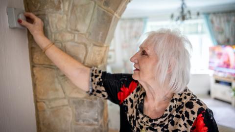 Old lady changing heating on thermostat